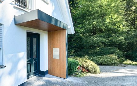 Vordach Serie S.1 in L-Form. Innenseite mit Fassadenplatte in Optik Holzdekor